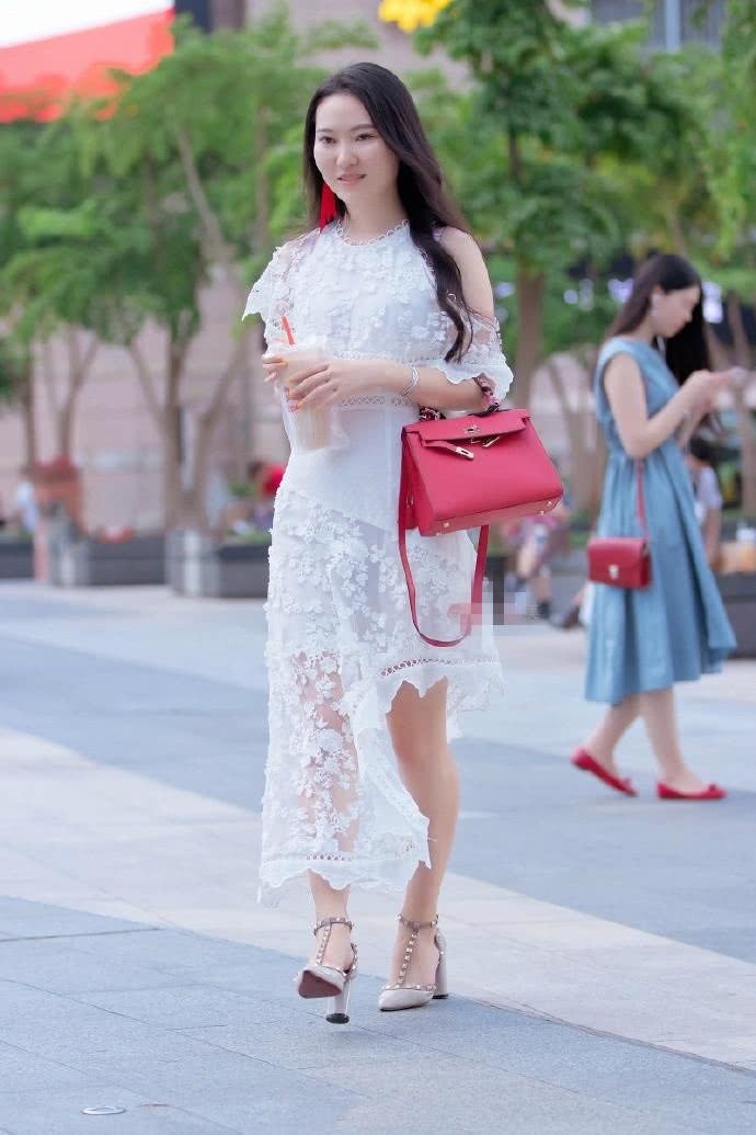 路人街拍:小姐姐穿着一件不规则长裙,脸上的微笑养眼又甜美!
