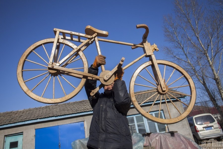 2016年1月7日,65岁的老农李景阳举起他发明的木制自行车说"很轻".