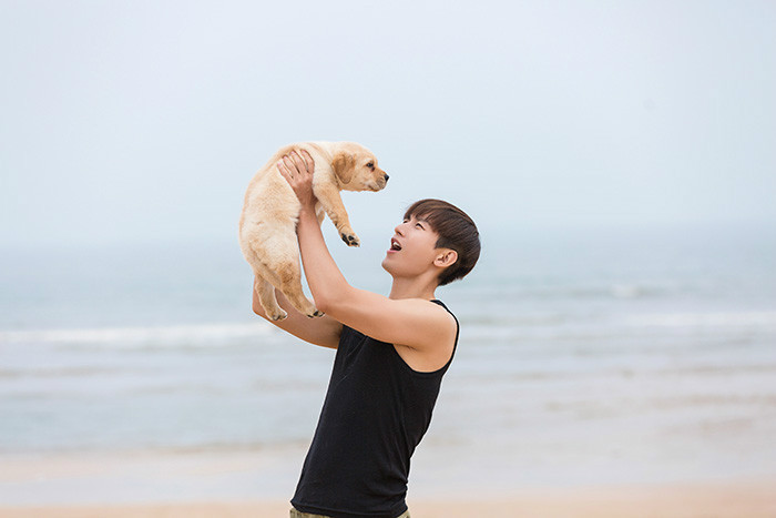 主角成毅与爱犬拉布拉多在海边嬉戏玩耍的写真照片,成毅化身"奶爸"与